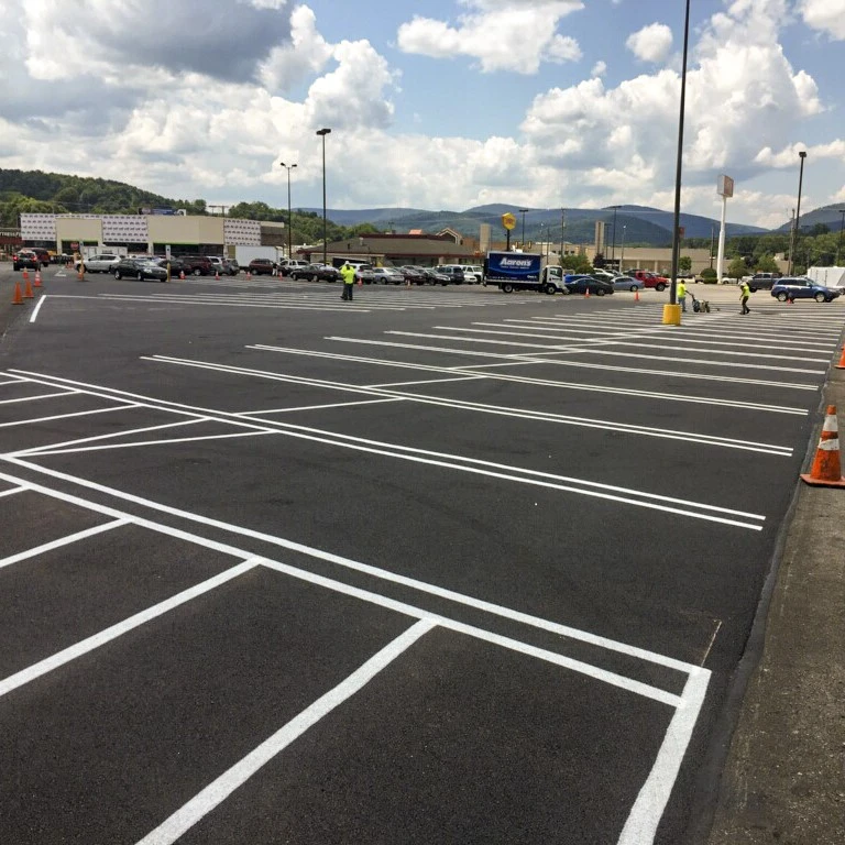 Freshly striped and paved parking lot with clear white lines under a partly cloudy sky, showcasing a newly completed asphalt project.